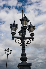 Fototapeta na wymiar Looking up at street lights of Bordeaux, dark cloudy skies background