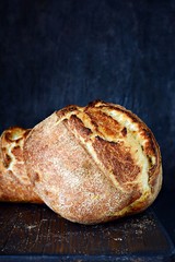 Homemade Freshly Baked Country Bread  made from wheat and whole grain flour on a dark background. French Freshly baked bread. Slicing homemade bread 
