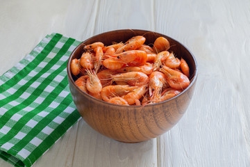 Fresh cooked sea shrimps in a bowl on a white wooden background. Seafoood. Sea products macro. Black sea shrimp.