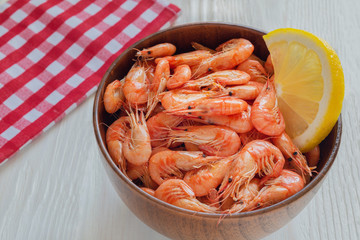 Fresh cooked small sea shrimps in a bowl on a white wooden background. Seafoood. Sea products macro. Black sea shrimp.