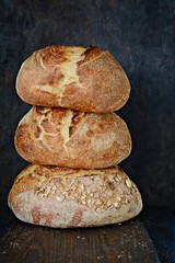 Homemade Freshly Baked Country Bread  made from wheat and whole grain flour on a dark background. French Freshly baked bread. Slicing homemade bread 