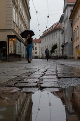 A lady walks through the streets of Graz on a rainy day