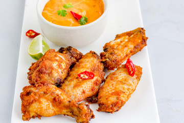 Crispy Oven Fried Chicken Wings in a Platter with Dip Sauce, Red Chili and Lemon Wedges Top View Food Photo
