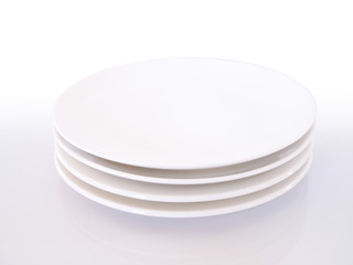 Stacked white ceramic plates, empty round dish isolated on white background.