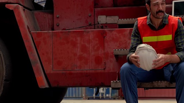 panning video shot of engineers are sitting on a forklift in a transportation industry site. He is very tired at work
