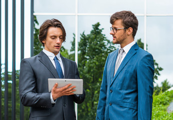 Confident businesspersons in formal wear having conversation about banking and financial markets in front of office building.