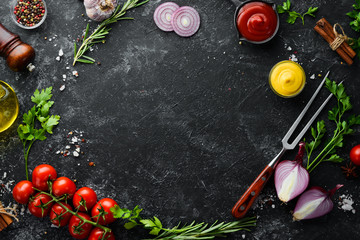 Black stone cooking background. Spices and vegetables. Top view. Free space for your text. - obrazy, fototapety, plakaty