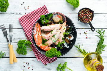 Boiled Seafood in a creamy sauce on a black stone plate. Seafood, prawns, shellfish, lobster. Top view. Free copy space.