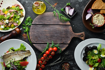 Food. Set of salads and dishes on black stone background. Top view. free space for your text. Rustic style.