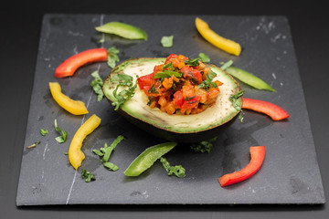 Vegan food: avocado filled with pepper, zucchini and basil 