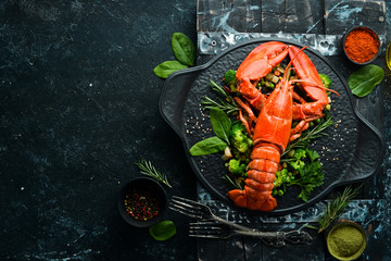 Boiled lobster with vegetables on a black stone plate. Seafood. Top view. Free space for your text.