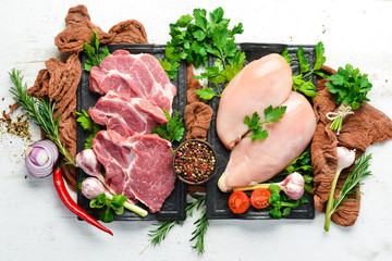 Veal meat and chicken breast with spices. Top view. On a white wooden background. Free space for your text.