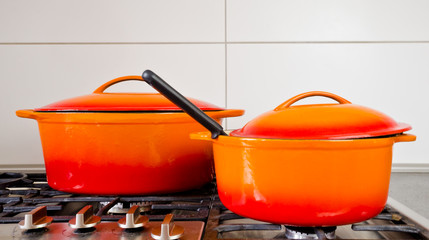 two bright orange pots from cast iron with enamel at an old vintage gas stove