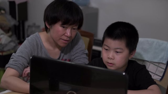 Chinese kid and mother doing online homework amid coronavirus pandemic.