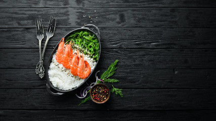 Asian food. Rice, shrimp and salad Chuka in a black bowl. Rustic style. Top view. Free space for your text.