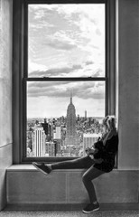 young woman watching a new york cityscape and skyline from window in manhattan in new york, USA