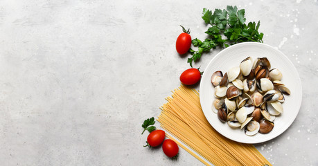 seafood pasta ingredients: clams, spaghetti, tomatoes and parsley. recipe for traditional Italian pasta Spaghetti alle Vongole. on a gray background. top view, food flat lay