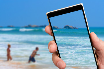 Ocean waves on smartphone screen. Summer sunny day in tropics. Soft focus.