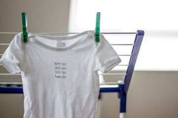 Happy day every day - concept for love at home with baby shirt hanging on clothes horse (no people)