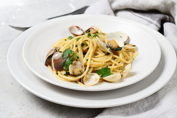 Traditional italian food seafood pasta with clams and parsley Spaghetti alle Vongole in white plates on a grey background. top view
