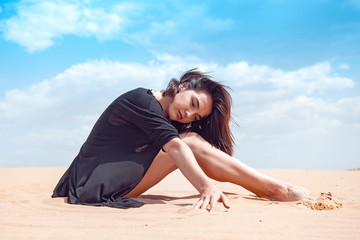 Fototapeta na wymiar Beautiful girl in black swimsuit in the desert