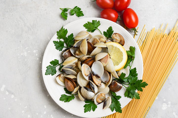 seafood pasta ingredients: clams, spaghetti, tomatoes and parsley. recipe for traditional Italian pasta Spaghetti alle Vongole. on a gray background. top view, food flat lay