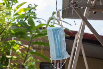 Fototapeta na wymiar Reused surgical mask is hanging with hanger by clip to dry from sun light for sterilize outside.