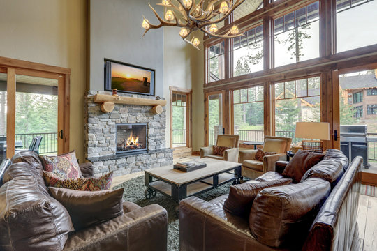 Amazing two story tall living room interior  with sky bridge and leather furniture.