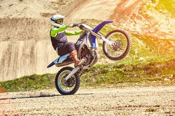 Motocross, a rider stands on the rear wheel of a bike, Riding on the rear wheel. Extreme,...