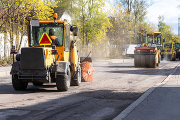 Tractor with spinning brush cleaning newly laid asphalt. Reconstruction and repair of a street...