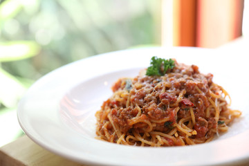 spaghetti Bolognese with minced beef and tomato sauce garnished with parmesan cheese and basil , Italian food