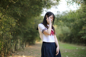 Portrait of beautiful Asian japanese high school girl uniform looking with bamboo forest background