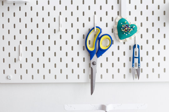 Tools For Working In The Sewing Workshop Scissors, A Needle Case With Needles Hanging On A Peg Board, As An Idea For Storage In A Craft Room Or Workshop