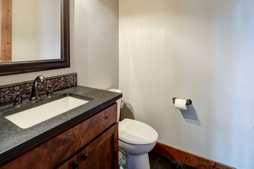 New rustic luxury home bathroom for guest design details with rich wood and grey stone with natural tiles on the floor.