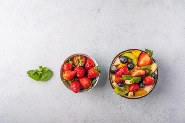 Fresh fruit salad with different ingredients and mint on light background. Healthy diet. Copy space for text. Top view