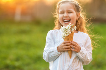 little girl with waffle cone filled, blooming cherry branches, holding her hand