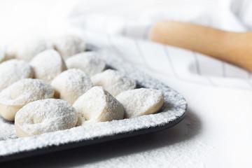 Fototapeta na wymiar meat dumplings lie on a tray, near flour and rolling pin, sculpt dumplings