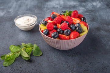 Fresh fruit salad with different ingredients with mint and sour cream on dark background. Healthy diet. Copy space for text. Close up