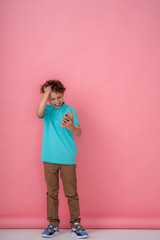 happy boy holding a smartphone on a pink background