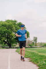 A young athlete in a blue T-shirt runs around the stadium