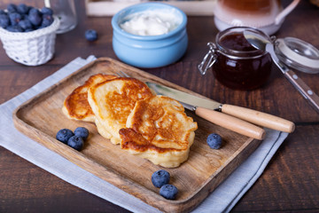 Fritters with sour cream, jam and blueberries. The traditional Russian dish. Close-up.