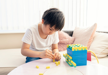 School kid using plastic block counting number,Child boy studying math by colour stack box,Montessori classroom material for children learning of mathematics at home,Home schooling, Distance education