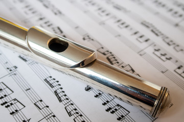View of a shiny transverse flute placed on a music sheet