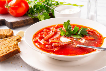borscht with sour cream and parsley in a  plate, red Ukrainian  soup with bread,