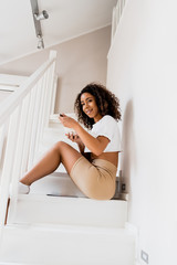 happy african american woman sitting on stairs and holding breakfast in bowl