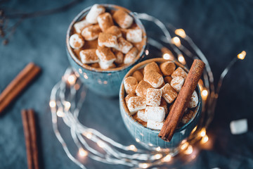 Hot chocolate with marshmallow and cinnamon in blue ceramic cups on a table. The concept of cosy holidays and New Year.