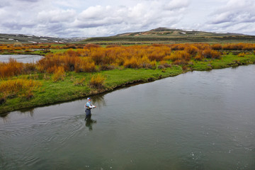 Fototapeta na wymiar an aerial shot of a man fly fishing on a river.