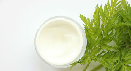 jar of face cream, body with green, exotic leaves nearby, on a light background. Natural Care, Organic Cream, Moisturizing, Care, Beauty, Makeup Production