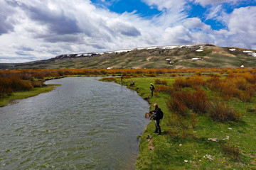 Fototapeta premium An aerial view of Two men fly fishing on a river.