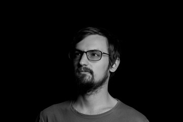 portrait of a guy with a beard in glasses on a black background